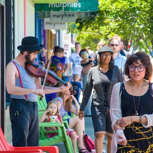 Pedestrians walking by musician playing violin on Cary St.