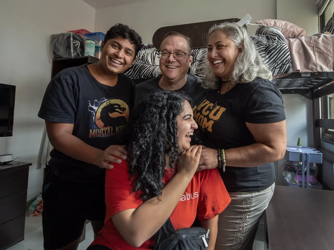 Family posing with a student in a dorm room