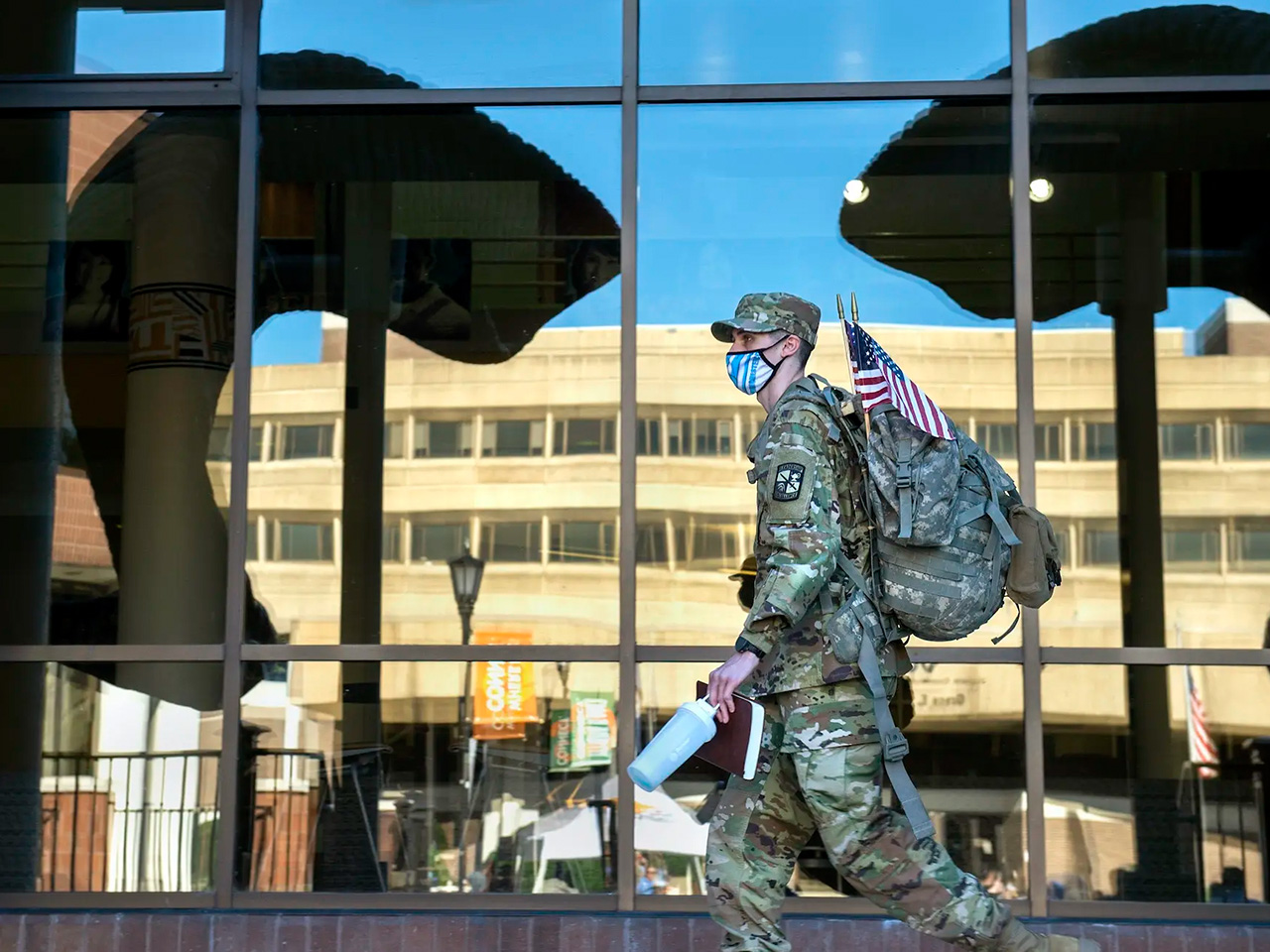 A student in military clothing walks through the Commons