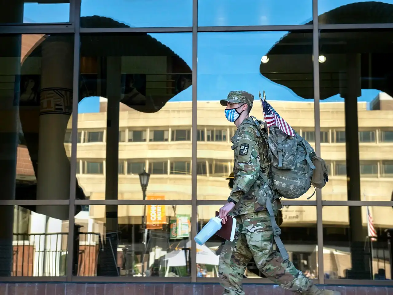 A student in military clothing walks through the Commons.