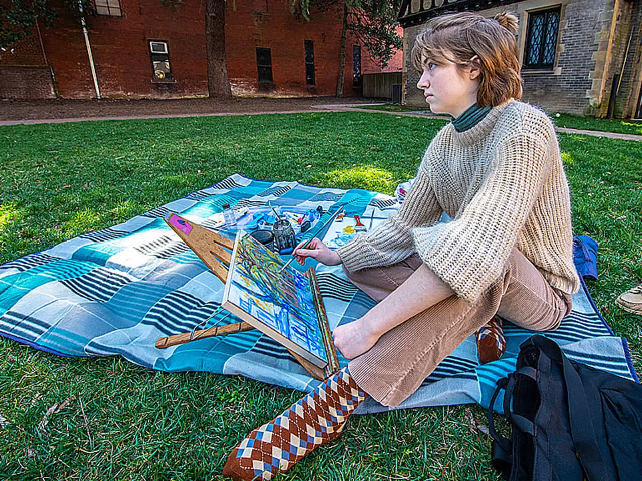 Student sitting outdoors while painting.