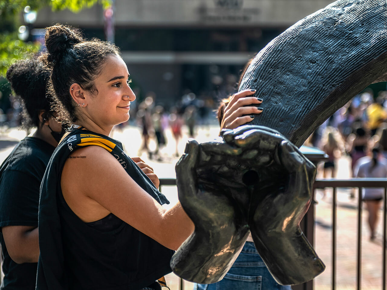 Student standing with the large ram horn sculpture on campus
