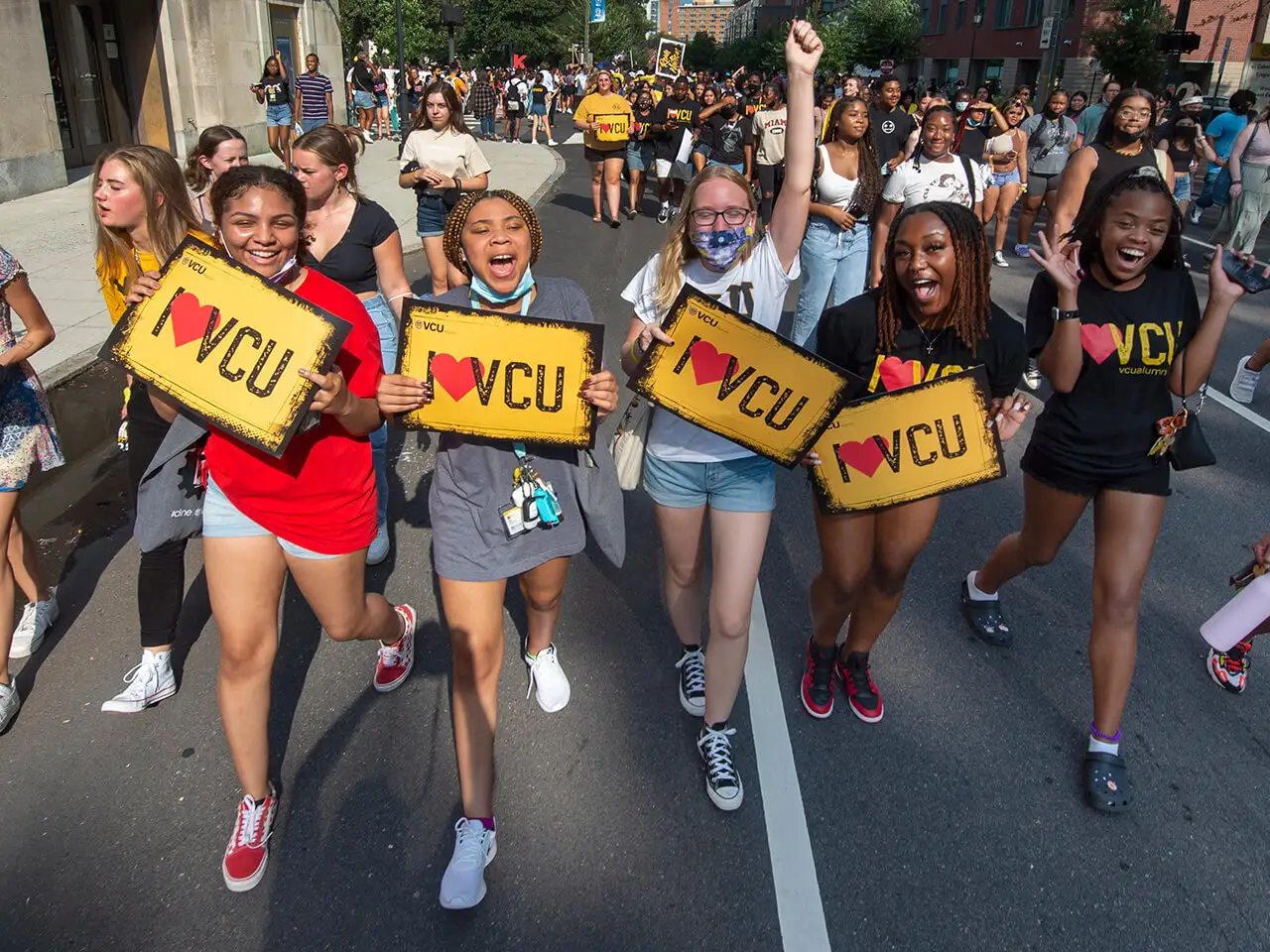 Students walking together holding I love VCU signs.