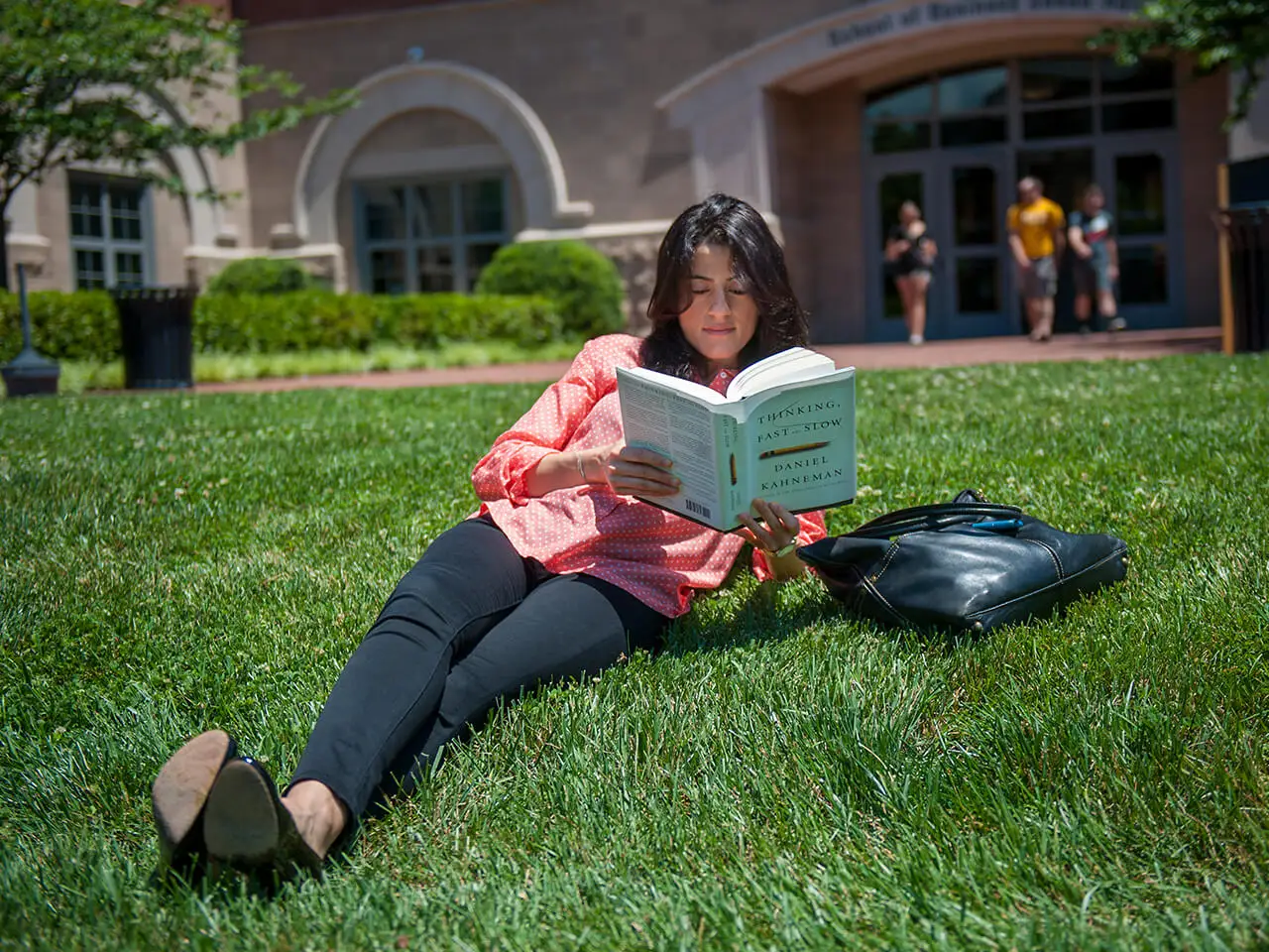 Woman laying in the grass reading a book.