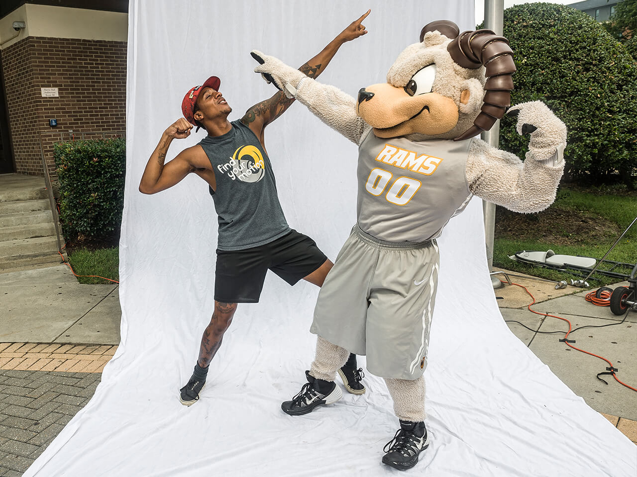 Student in a pointing upward pose with mascot in same pose