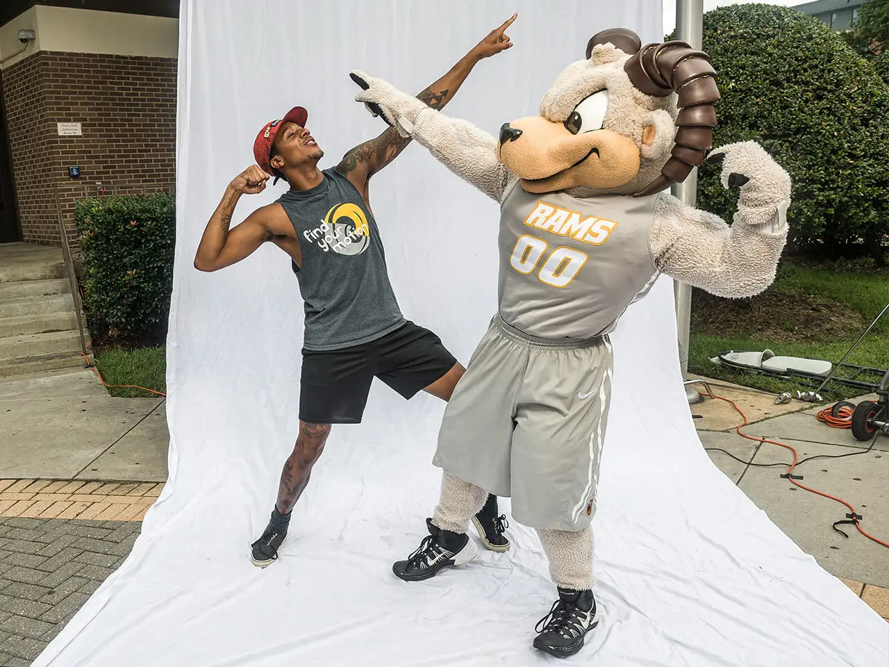 Student in a pointing upward pose with mascot in same. pose