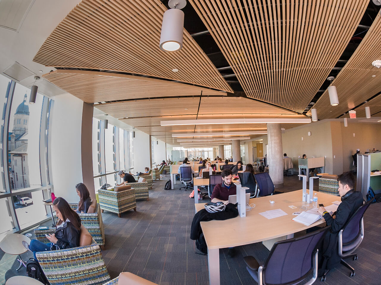 Students sitting at tables in the library studying