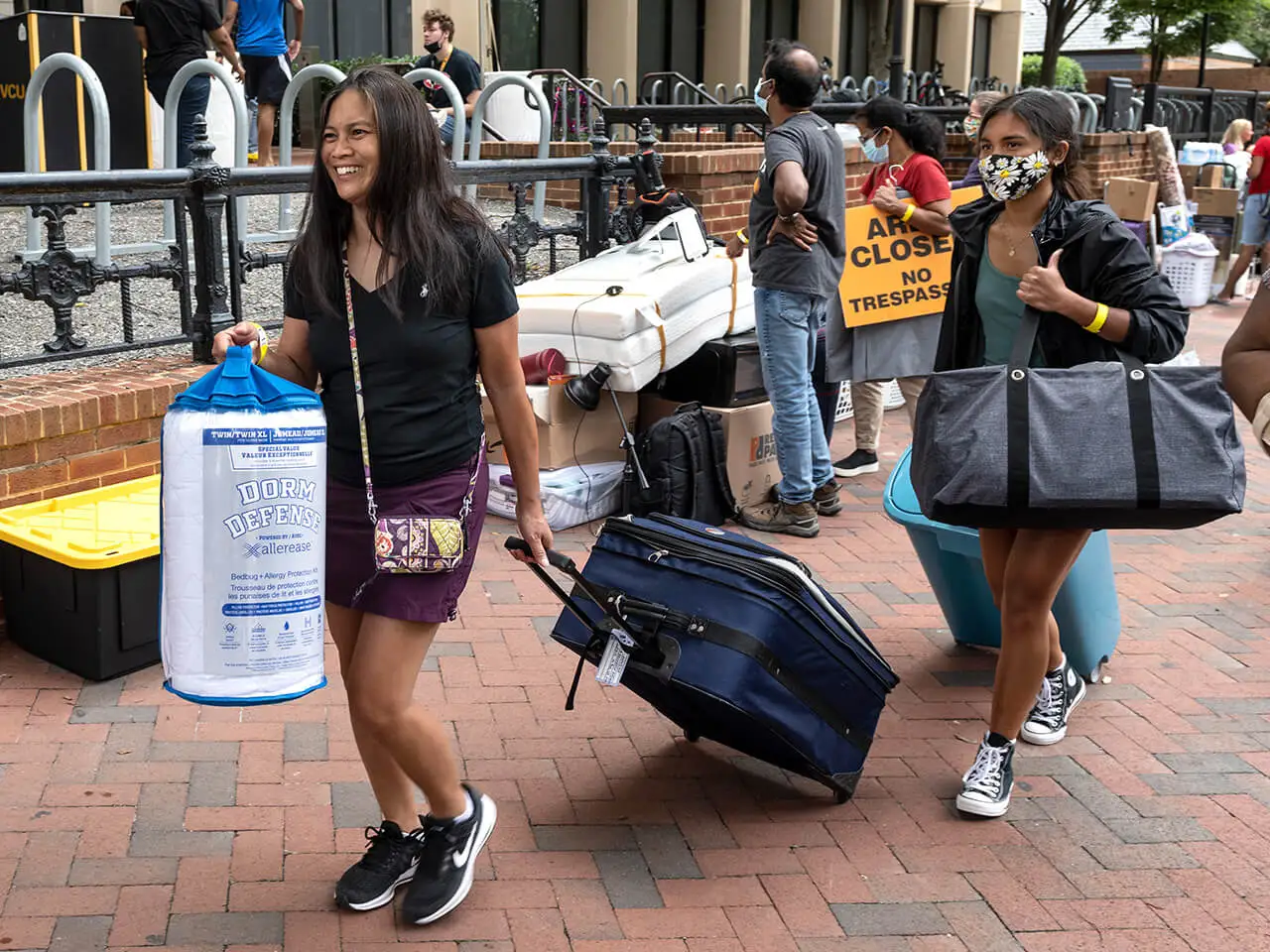 Students moving into the dorms carrying luggage.