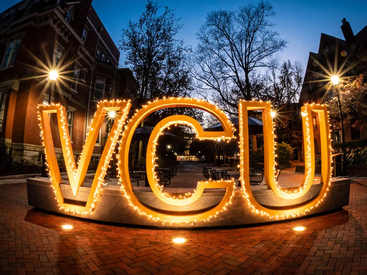 VCU in gold letters lit up at night with lights.