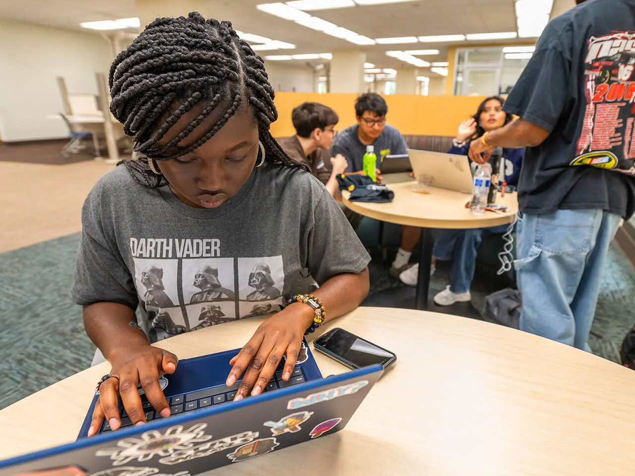 A student sits at a desk looking intensely at a laptop