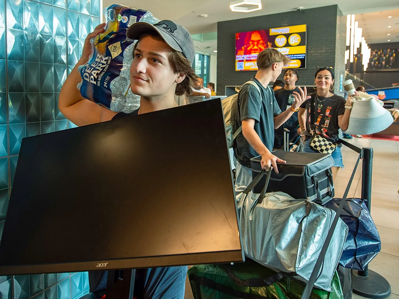 Student waits in line for an elevator holding a television during move in day